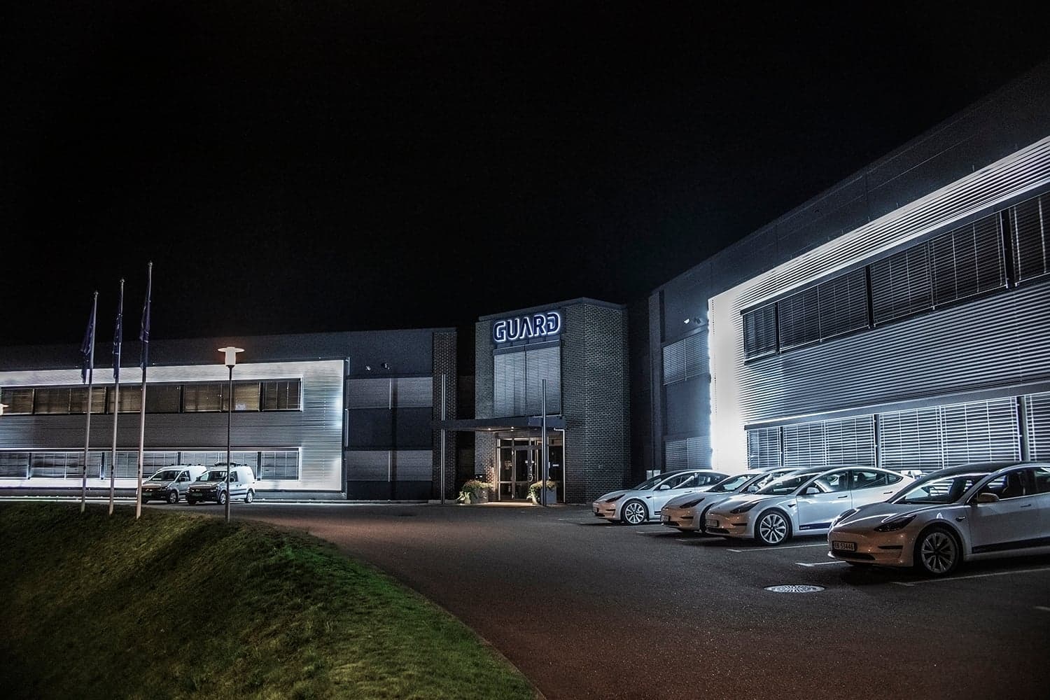Guard headquarter at night, seen from the front with white Tesla company cars lined up