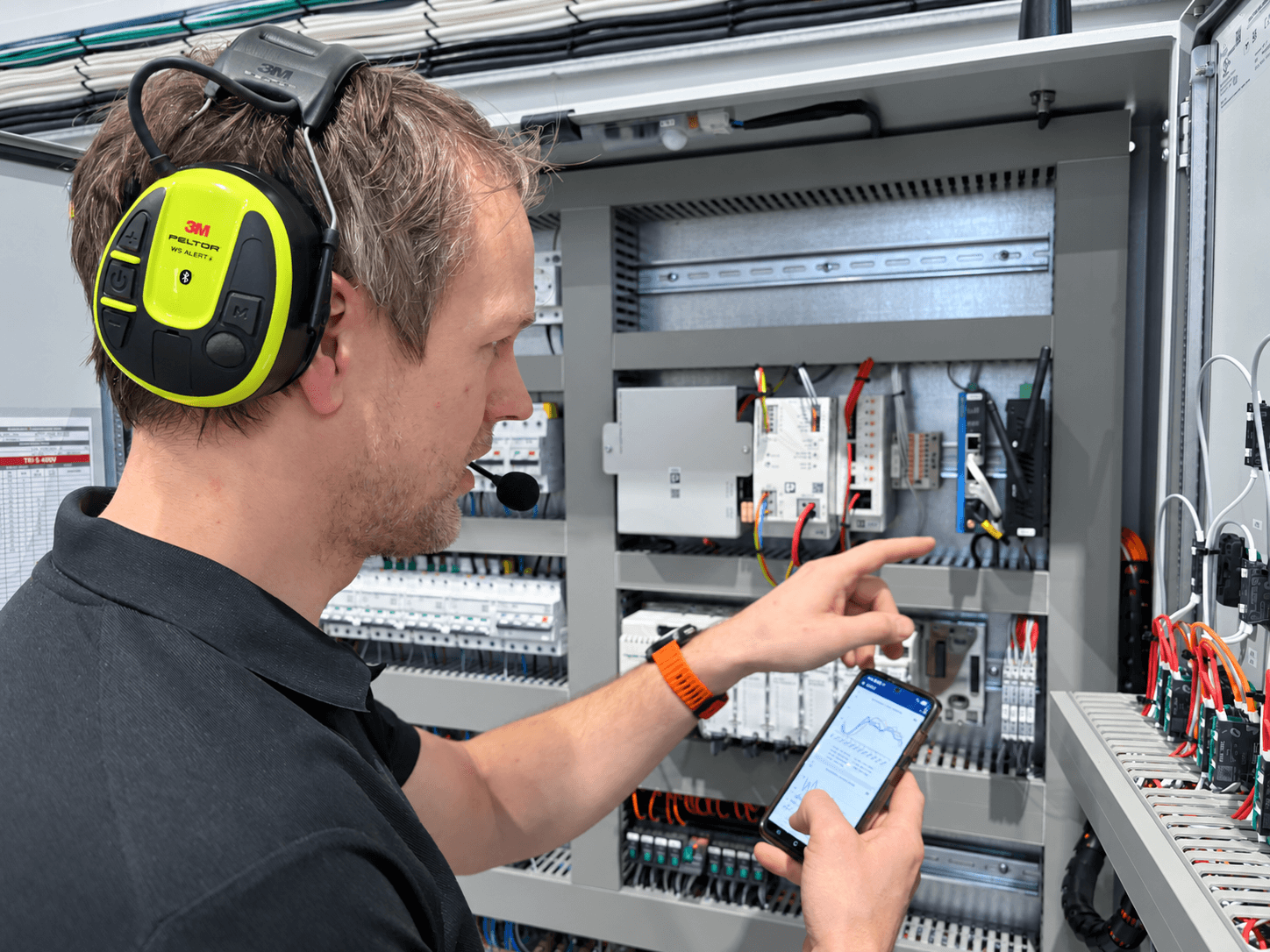 Guard employe stands in front of the control panel and the digital hmi solution in his hans
